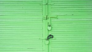 A green garage door with decorative hardware that an owner used garage door ideas for curb appeal to enhance